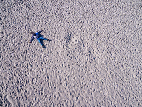 Aerial view of a chilf lying alone on a sandy beach