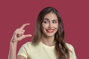 Smiling woman showing hand fingers small distance