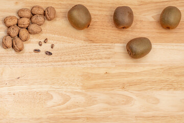 Top view of walnuts, kiwis and pine nuts with copyspace on a wooden table