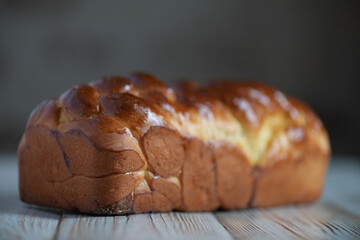Loaf of homemade wicker white bread on a wooden background, close-up.