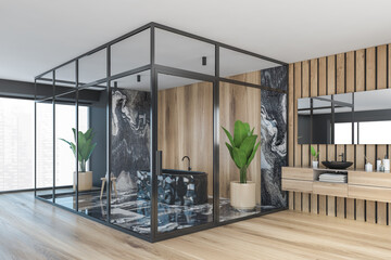Dark marbel and wooden bathroom modern interior with a wooden floor, a black ceramic tub, a tree in a pot, panoramic window, double sink.