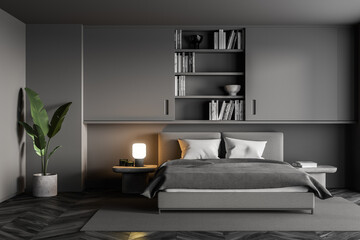Grey bedroom with bed and linens, bookshelf and plant on parquet floor