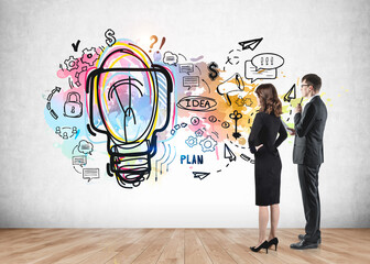 Two young business partners looking at colourful business idea sketch on wall