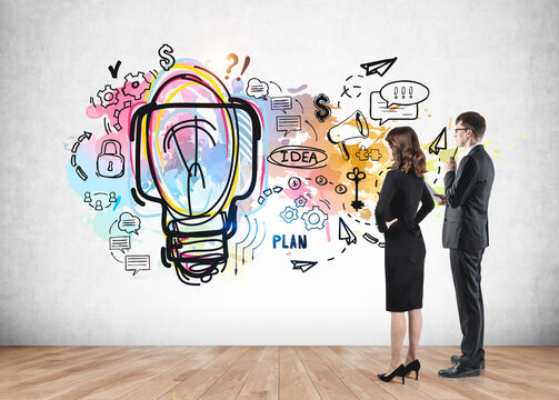 Two young business partners looking at colourful business idea sketch on wall