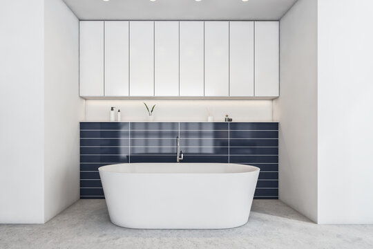 White and blue bathroom with white bathtub on grey marble floor