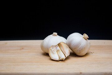The garlics isolated black background on a wooden cutting board