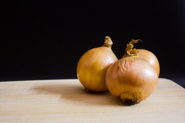 The yellow onions isolated black background on a wooden cutting board