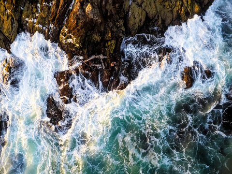 Surfcaster Fisherman on ocean rocks as seen by Aerial Drone