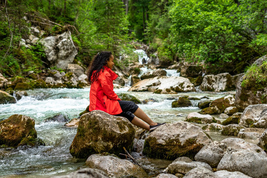 Young woman sitting on a rock in a turquoise river in the forest