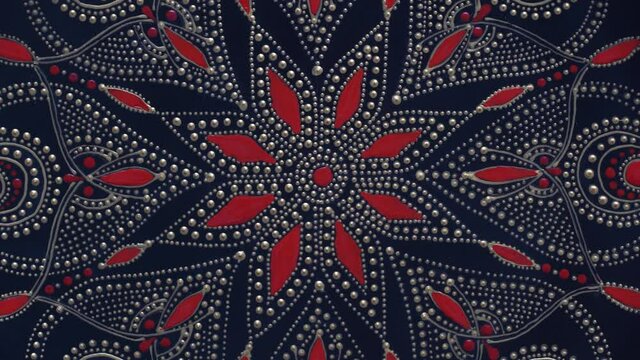 Decorative ceramic plate with black, red and golden colors, painted plate on background, closeup, top view, rotate. Decorative porcelain plate painted with acrylic paints, handwork, dot painting