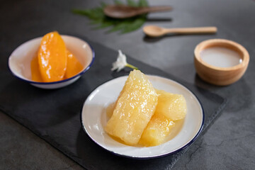 Cassava and Yam in syrup usually served coconut milk in vintage zinc coating dish on black stone background. Traditional desserts in Thailand.