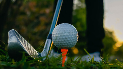 tee stand on grass hole tee and golf ball at sunset