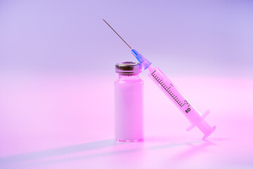 Close up glass vial with flu vaccine and syringe with needle. The concept of vaccination or preventive treatment of injection diseases.