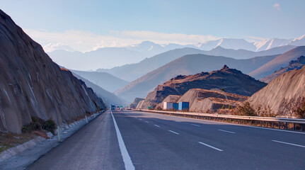 Perspective asphalt highway road with cars in the form of mirage, Taurus mountain in the background