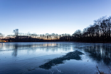 frozen ice surface of Decksteiner Weiher lake in Cologne at sunrise