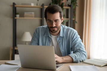 Attentive millennial male manager employee busy at telework at quarantine time study documents in...