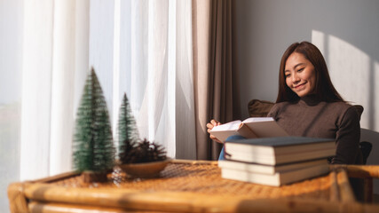 Closeup image of a beautiful young asian woman reading book at home