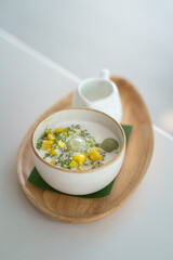 Sago or Saku topping with corn, longan fruits and coconut milk, served in white bowl on the wooden plate. This is one of famous tradition Thai dessert food. Sweet food close-up photo.
