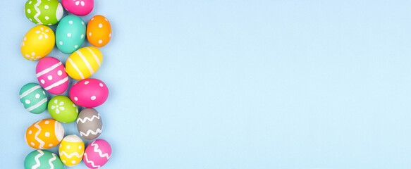 Colorful Easter Egg side border over a pastel blue paper banner background. Copy space.