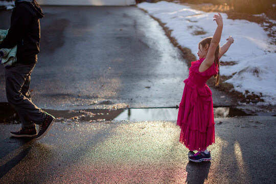 A little girl lingers behind her father on a walk, dancing in street