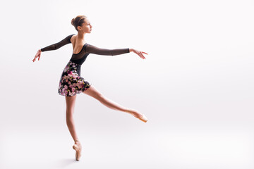 Ballerina in black pointes posing in graceful pose on white background