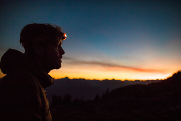 Portrait of mountaineer wearing headlamp at dusk in the mountains
