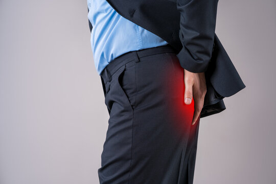 Office worker suffering from hemorrhoids, anal pain on gray background