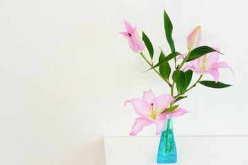 青いガラス瓶に生けられたピンクの百合