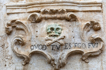 A bas-relief with a skull and a Latin inscription from the facade of the Church of Purgatorio in Gravina in Puglia. Italy