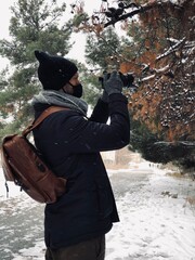 black and white winter portrait of a man holding his camera and wears jacket scarf and camera in a snow location 