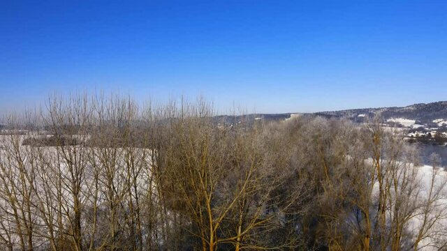 Drone rising over beautiful bavarian winter landscape with snow and famous landmark Walhalla over the Danube river in background on clear sunny day
