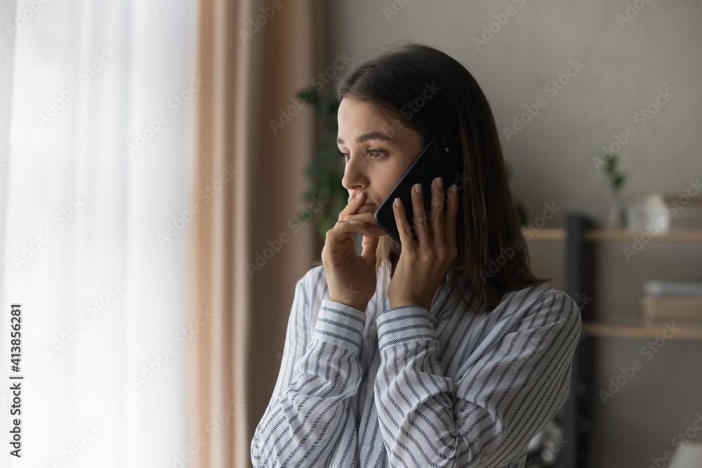 Wall mural sad millennial woman has difficult phone talk hold gadget by ear listen to unexpected bad news think