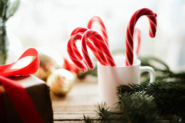 Close-up of candy canes in cup by baubles and twig on wooden table