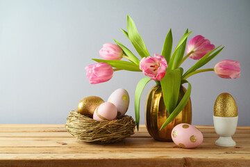 Easter holiday concept with beautiful tulip flowers, pink and golden eggs on wooden table