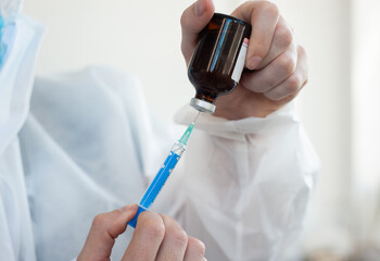 Close-up of a man's hand holding a syringe with a needle and a vaccine against the virus and preparing it for vaccination. Vaccination against coronavirus. Vaccine for pandemic