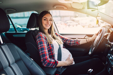 Beautiful pregnant happy woman driving car.