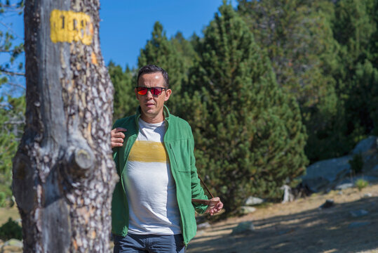 Portrait of adult man wearing sunglasses in a forest looking away
