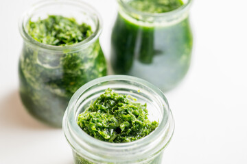 Pesto sauce in three jars on a white background