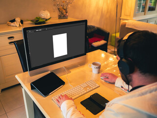 Teleworking - Young man working from his home in his living room, on his computer and his tablet - graphic designer - back view