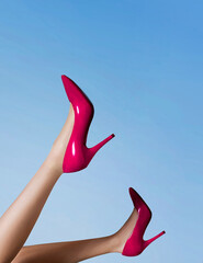 Woman wearing red high heel shoes in the blue sky. 