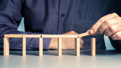 Man build a small bridge with wooden domino and try to expand the length, risk to make it all down
