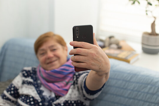 The Happy Elderly Woman At Home Takes A Selfie