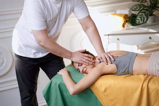 masseur works at home. man makes a beautiful woman massage