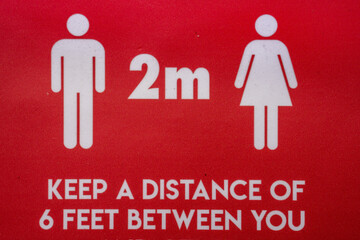 close up view of red and white social distancing sign for coronavirus regulations