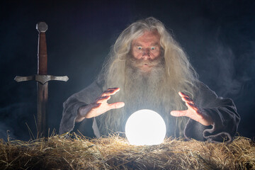 Wizard with long beard an hair looking in magic ball to se future