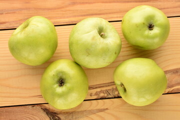 Several ripe green apples on a wooden table, close-up, top view.