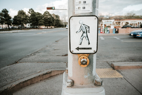 Walk signal sign with street art skeleton painted on by crosswalk