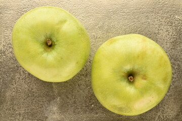 Two juicy green apples on a metal tray, close-up, top view.
