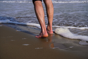 Piedi scalzi sulla spiaggia e onda che li bagna