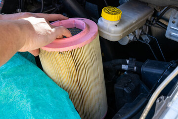 close up of hands of a caucasian male car mechanic changing the air filter in an engine